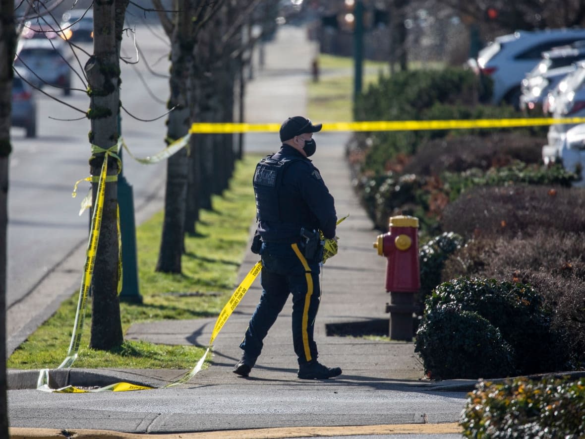 An RCMP officer at the scene of a stabbing in February 2022 at 228 Schoolhouse St., in Coquitlam, B.C., that claimed the life of a 66-year-old man. Two men in their 20s have now been arrested and charged. (Ben Nelms/CBC - image credit)