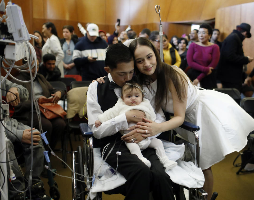 In this Wednesday, Nov. 27, 2019 photo, Javier Rodriguez and Crystal Cuevas hold their four-month-old daughter Leia as they celebrate during their wedding before family, friends and medical staff in the chapel at the University of Chicago Medical Center for Care and Discovery in Chicago. Rodriguez, 23, who received two heart transplants as a teenager died in hospice care, days after he married his high school sweetheart, his new bride said. (Brian Cassella/Chicago Tribune via AP)