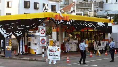 Swiss police officers watch members of Greenpeace during a protest at a Shell gas station in Zurich June 30, 2015. REUTERS/Arnd Wiegmann