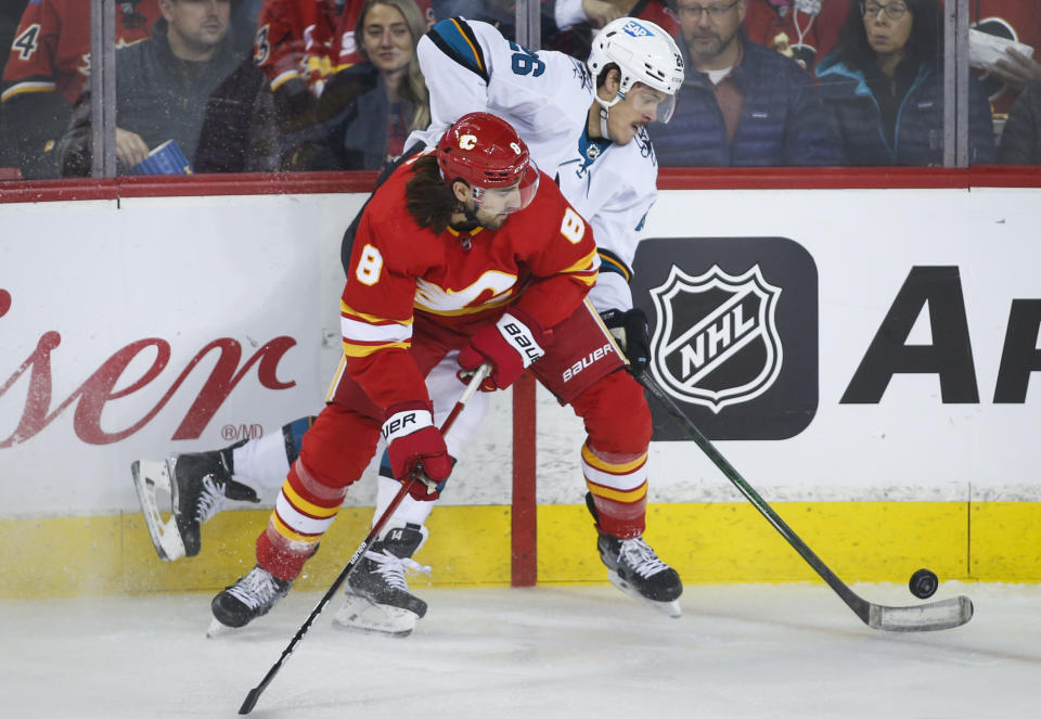 San Jose Sharks' Jasper Weatherby, right, is checked by Calgary Flames' Christopher Tanev during the first period of an NHL hockey game, Tuesday, Nov. 9, 2021 in Calgary, Alberta. (Jeff McIntosh/The Canadian Press via AP)