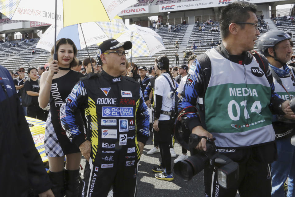 Toyota Chairman Akio Toyoda, center, stands next to the racing car powered by liquid hydrogen he drove during a 24-hour race at Fuji International Speedway in Oyama town, some 100 kilometers (62 miles) southwest of Tokyo, Saturday, May 27, 2023. The hydrogen-fueled Corolla has made its racing debut, part of a move to bring the futuristic technology into the racing world and to demonstrate Toyota’s resolve to develop green vehicles. (AP Photo/Yuri Kageyama)