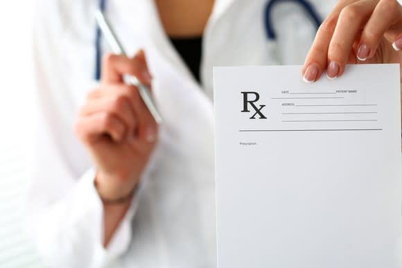 Image of a female doctor holding a prescription pad.