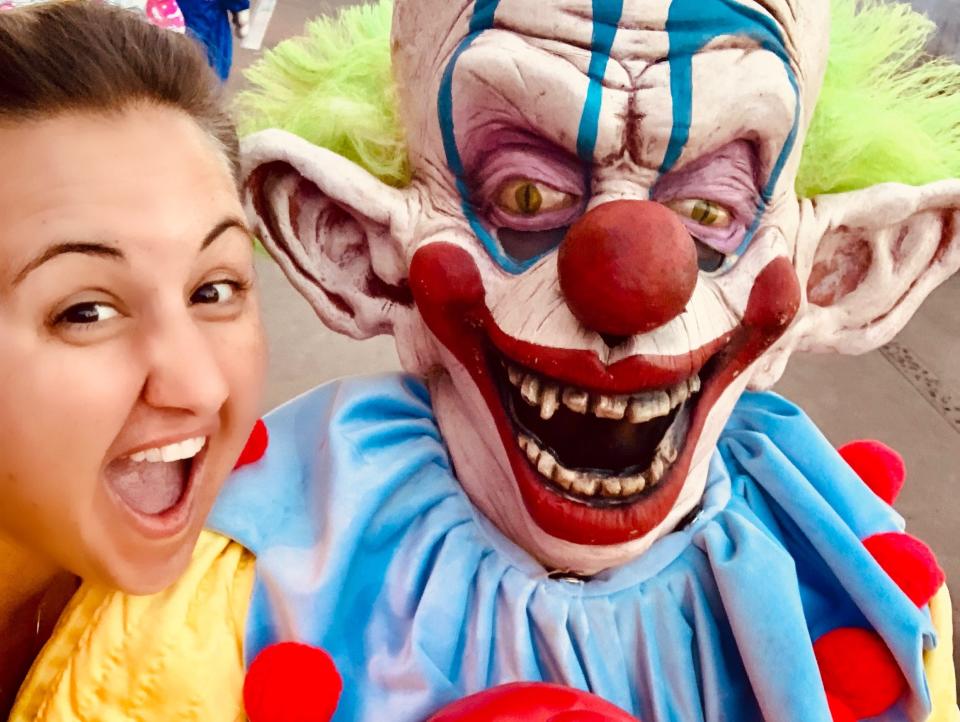Carly Caramanna next to a scary clown at universal's halloween horror nights