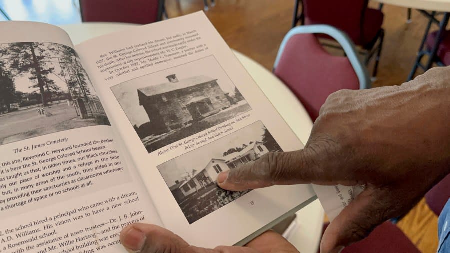 Ralph James points to an old photo of the Rosenwald School he has helped restore in St. George, S.C., on Tuesday, July 11, 2023. Jewish businessman Julius Rosenwald donated money to help build 5,000 schools for Black students across the American South a century ago. Only about 500 are standing and roughly half of them have been restored. (AP Photo/Jeffrey Collins)