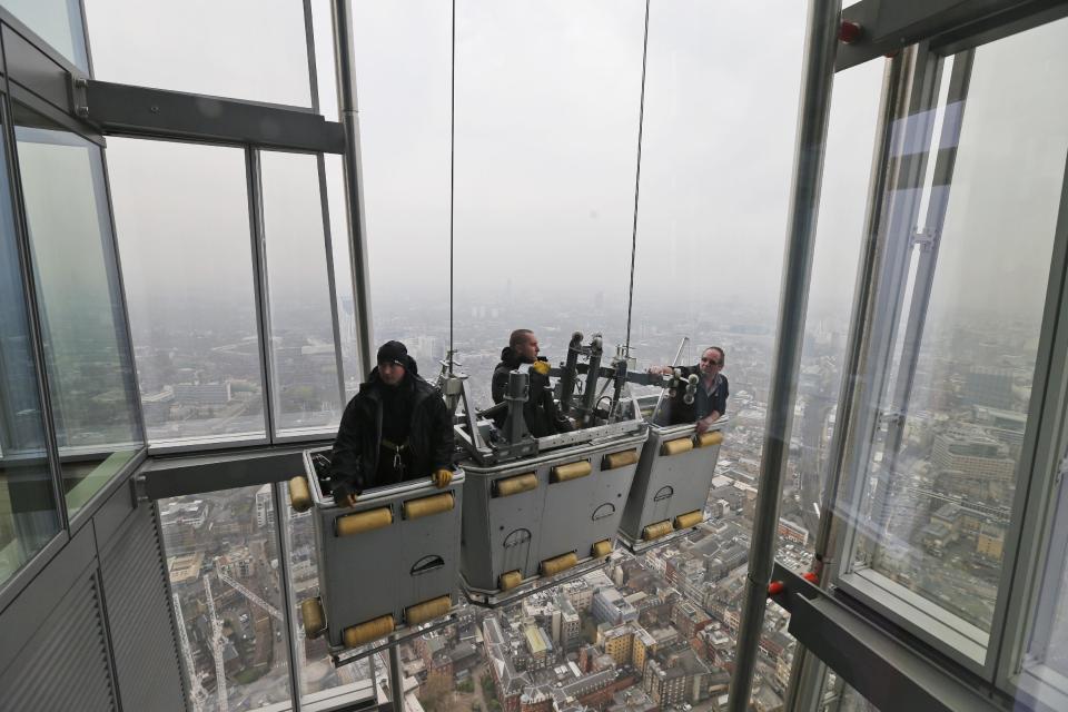 Maintance personnel are seen from the viewing platform of a skyscraper in central London, Thursday, April 3, 2014. British authorities have warned people with heart or lung conditions to avoid exertion as a combination of industrial pollution and Sahara dust blankets the country in smog. The environment department said air pollution level could reach the top rung on its 10-point scale. The pollution is expected to ease by Friday. (AP Photo/Lefteris Pitarakis)