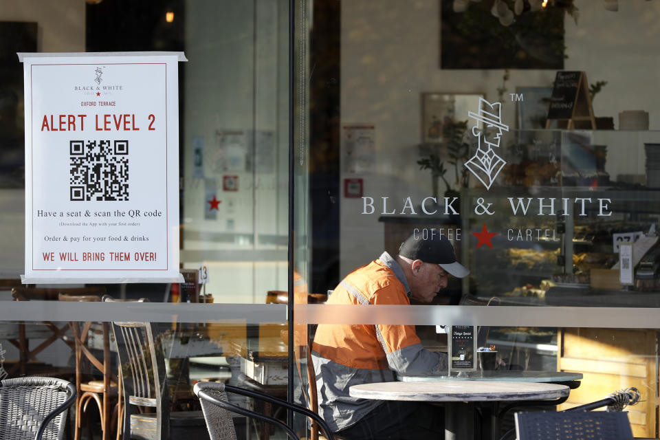 A man enjoys coffee in a cafe in Christchurch, New Zealand, Thursday, May 14, 2020. New Zealand lifted most of its remaining lockdown restrictions from midnight Wednesday as the country prepares for a new normal. Malls, retail stores and restaurants are all reopening Thursday in the South Pacific nation of 5 million, and many people are returning to their workplaces. (AP Photo/Mark Baker)