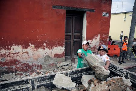 A municipal worker and a firefighter (R) remove debris from a damaged house after an earthquake in Antigua, Guatemala June 22, 2017. REUTERS/Luis Echeverria