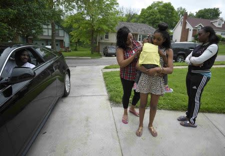 Auto worker Jermaine Austin (L), who works for General Motors, looks at his wife Akema (C), and daughters Jayla, 2, Armoni, 15, and Niya (R), 17, as he leaves to a new job, in Kansas City, Missouri May 16, 2015. REUTERS/Ed Zurga