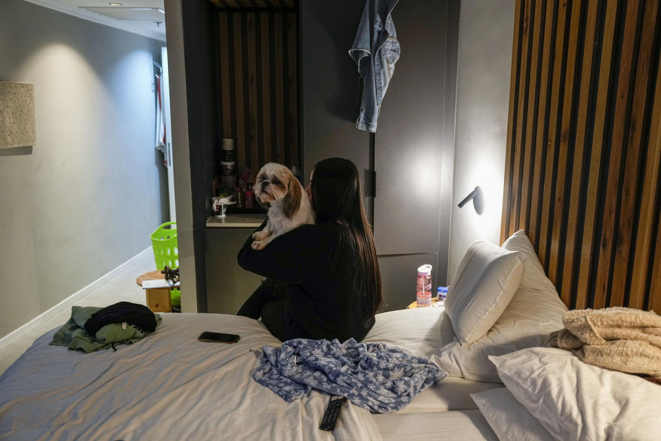 Maya Elharar, evacuated with her family from Kiryuat Shmona, holds her dog in the hotel room in Tiberias, northern Israel, Monday, March 4, 2024. Around 60,000 Israelis who evacuated from cities and towns along the border with Lebanon are grappling with the question of when they will be able to return home. Hezbollah began launching rockets towards Israel one day after Hamas-led militants stormed into southern Israel on Oct. 7. (AP Photo/Ariel Schalit)