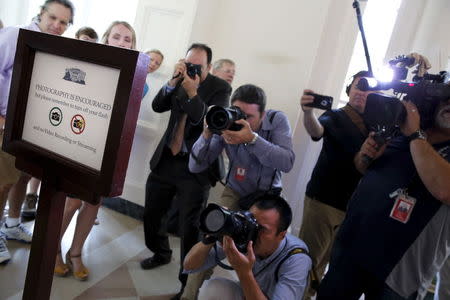 News photographers take pictures of signs announce that visitors can now take photos during tours of the White House in Washington July 1, 2015. REUTERS/Jonathan Ernst