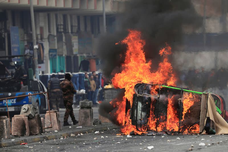 A tuk-tuk is burning after it was set on fire by Iraqi security forces during ongoing anti-government protests in Baghdad