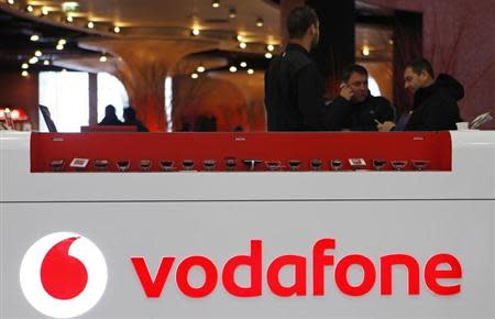 The Vodafone logo is seen at the counter of the shop as customers look at mobile phones in Prague February 7, 2012. REUTERS/David W Cerny