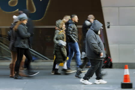 Pedestrians walk past a homeless man as he shuffles down a street in New York January 4, 2016. REUTERS/Lucas Jackson