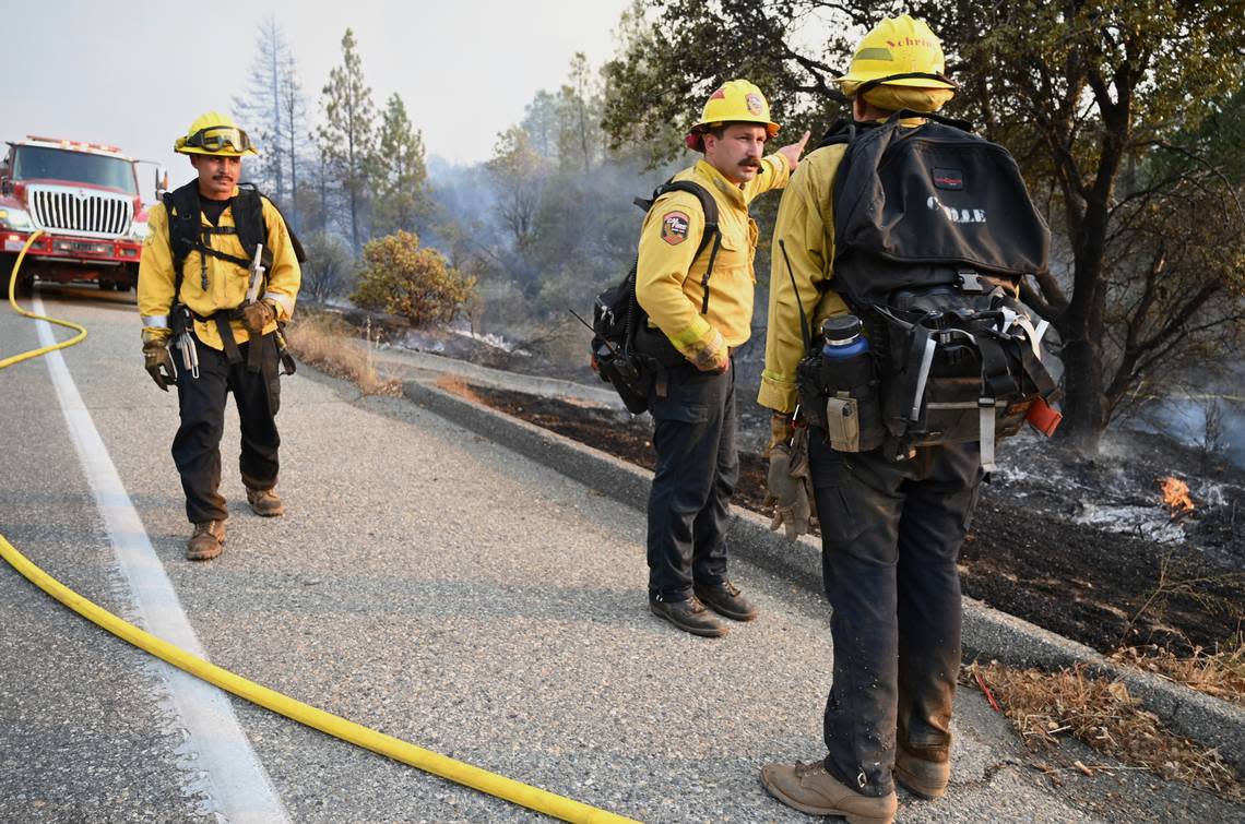 Firefighters stand along Road 225 as the Fork Fire burns near North Fork on Wednesday, Sept. 7, 2022.