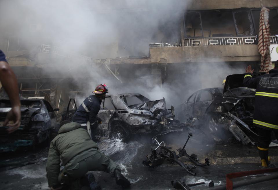 Civil defence members extinguish a fire at a site of an explosion in the Haret Hreik area