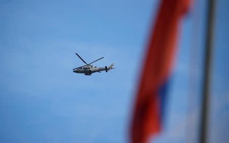 FILE PHOTO: A Philippine Air Force attack helicopter flies past a Philippine flag, after a bombing run at the Maute group positions in Marawi City, Philippines May 28, 2017. REUTERS/Erik De Castro/File Photo