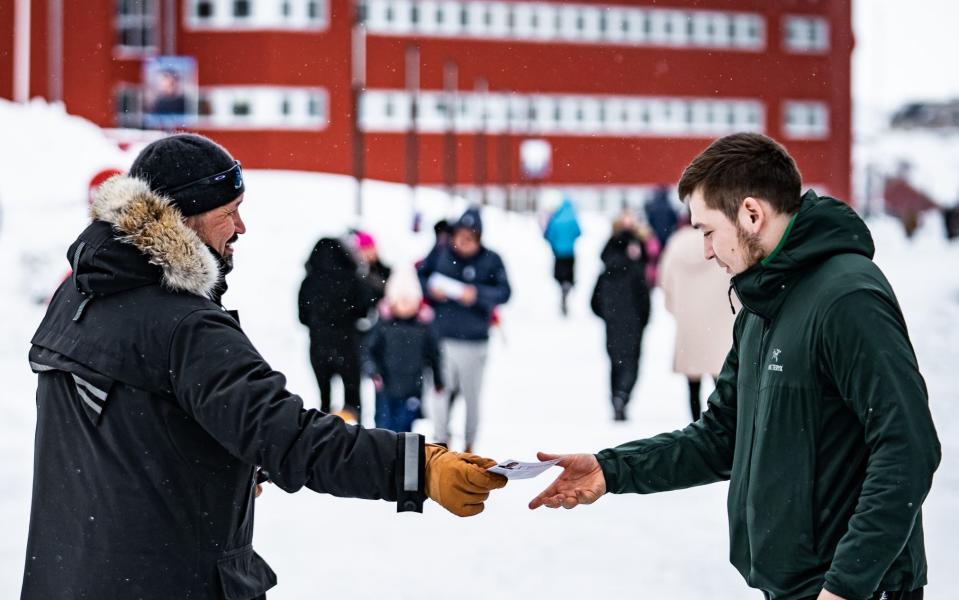 Candidates from the Siumut party hand out flyers in Nuuk, Greenland - Shutterstock