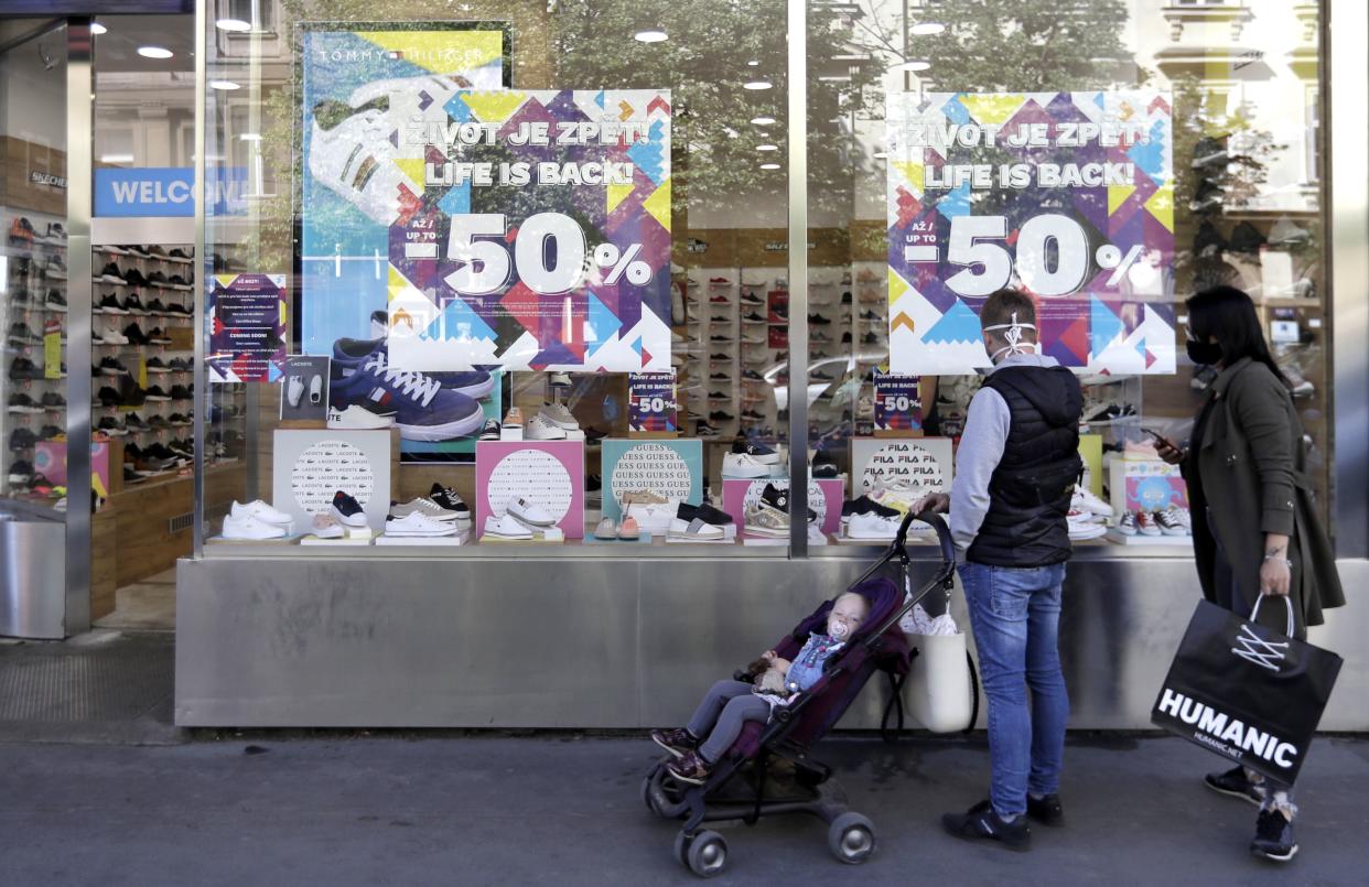 People look into the window of a shoe shop as stores reopen in Prague, Czech Republic on Monday, April 27, 2020. Most stores in Czech Republic were closed for over a month in efforts to stem the spread of the coronavirus.