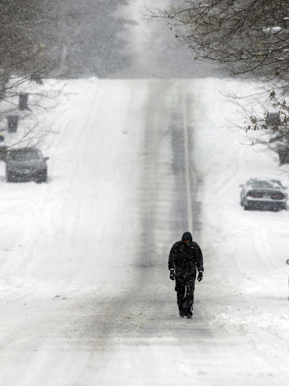 A pedestrian makes his way down a snow-covered street as snow continues to fall in Indianapolis, Thursday, Jan. 2, 2014. Over 5 inches of snow fell in Central Indiana. (AP Photo/Michael Conroy)