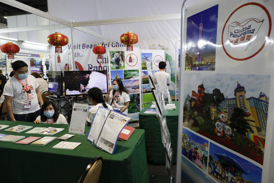 Workers wearing protective masks sit inside their booth promoting China during a travel fair in Manila, Philippines on Friday, Feb. 7, 2020. The organizer said the impact of travel bans due to the new virus has already affected tourism in the Philippines due to the huge Chinese market. Asian nations have profited handsomely from the impressive growth in tourists from China over the past decade, but the specter of a rapidly spreading virus has raised concerns over the industry prospects. (AP Photo/Aaron Favila)