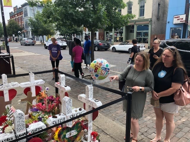 Sabrina Herman, gesturing, visits a makeshift memorial on Wednesday, Aug. 14, 2019, outside Ned Peppers nightclub in the Oregon District entertainment neighborhood where on Aug. 4 a gunman killed nine people, in Dayton Ohio. Herman, 41, of Dayton, a hospital social worker, visited with her sister, Tara Luikart, right, of Washington Court House. (AP Photo/Dan Sewell)