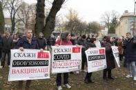 Demonstrators hold posters reading "Say no to mandatory vaccinations, say no to green passports, say no to digital ghetto" as they gather to protest against COVID-19 restrictions and vaccine mandates in Kyiv, Ukraine, Wednesday, Nov. 3, 2021. In a bid to stem contagion, Ukrainian authorities have required teachers, government employees and other workers to get fully vaccinated by Nov. 8 or face having their salary payments suspended. In addition, proof of vaccination or a negative test is now required to board planes, trains and long-distance buses. (AP Photo/Efrem Lukatsky)