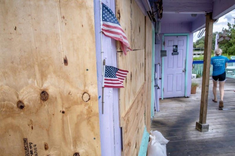 A person walks next to a restaurant covered with plywood as the town prepares for Hurricane Idalia in Cedar Key, Fla., on Tuesday. Hurricane Idalia slammed into Florida on Wednesday, Photo by Cristobal Herrera-Ulashkevich/EPA-EFE