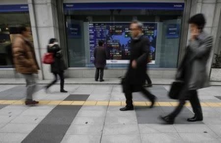 A man looks at an electronic board showing the stock market indices of various countries outside a brokerage in Tokyo January 26, 2015. REUTERS/Yuya Shino