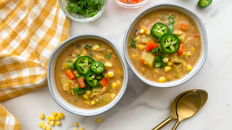 Two bowls of corn chowder with jalapeño garnish