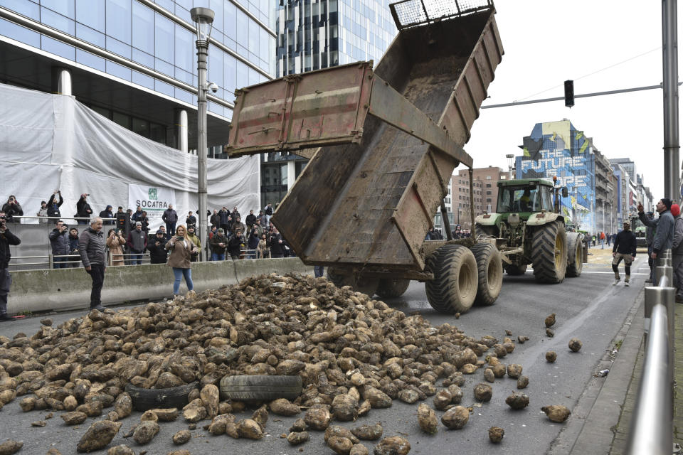 FILE - Protesting farmers dump a load of produce onto a main boulevard during a demonstration outside the European Council building in Brussels, on March 26, 2024. Across the EU, long convoys of tractors have cut off economic lifelines like ports and beltways around major cities, sometimes for days on end, with costs to industry running into the tens of millions daily and keeping hundreds of thousands of people from going to work. (AP Photo/Harry Nakos, File)