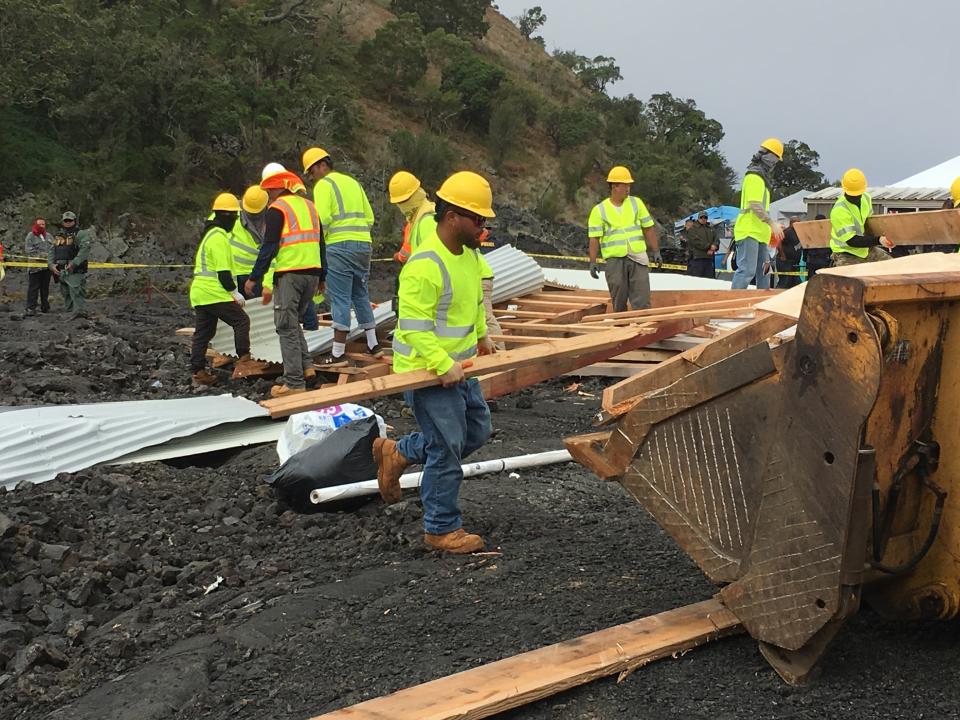 Crews and police gather at a lava field on Hawaii's Mauna Kea on the big island on Friday, Sept. 6, 2019 while a small wooden house is demolished. Opponents of a giant telescope built the unpermitted structure near their protest camp. (Dan Dennison/Department of Land and Natural Resources via AP)