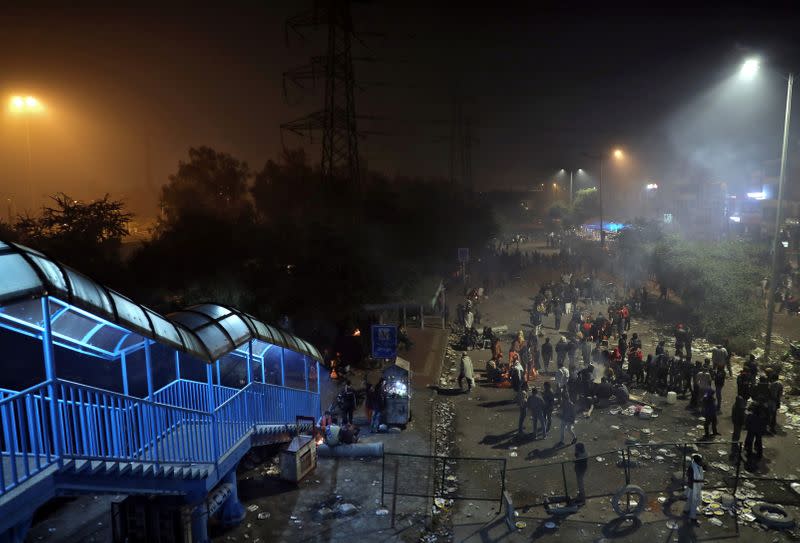 Local residents sit around bonfires to keep themselves warm as they block a road during a protest against a new citizenship law, in New Delhi