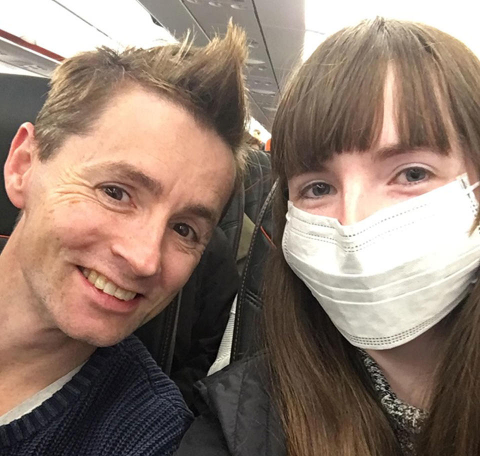 Courtney Ward, 25, and her partner Anthony Burns on board a plane. Ms Ward has a face mask on.