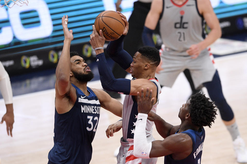 Washington Wizards guard Russell Westbrook, center, goes to the basket against Minnesota Timberwolves center Karl-Anthony Towns (32) and forward Anthony Edwards (1) during the first half of an NBA basketball game, Saturday, Feb. 27, 2021, in Washington. (AP Photo/Nick Wass)