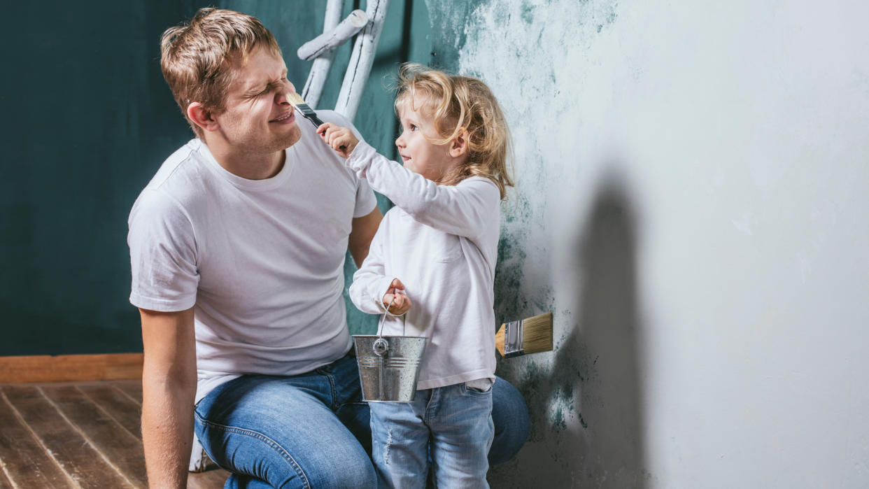 Family, happy daughter with dad doing home repair, paint walls, together with love.