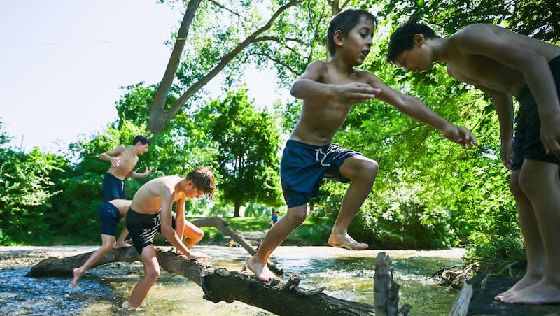 Cousins Tobler Hintze, Anders Hintze, Jack Shirley, Ollie Stout, and Elden Stout, play in the cool water of Parley’s Creek near Sugar House Park in Salt Lake City on Wednesday, July 10, 2024.
