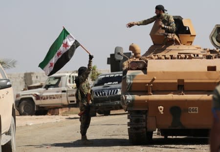 A Turkey-backed Syrian rebel fighter holds the Syrian opposition flag near the border town of Tel Abyad