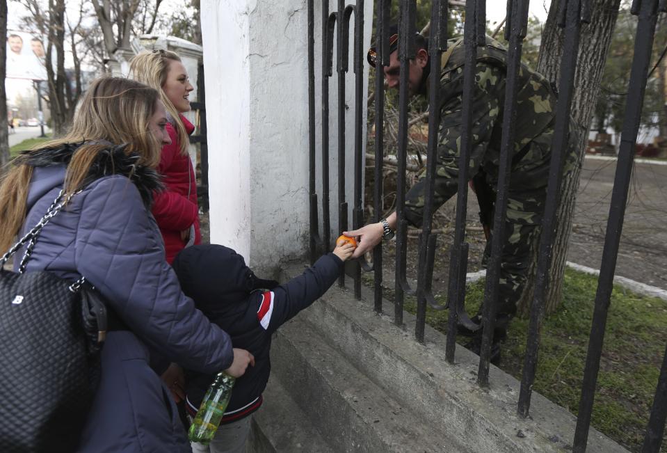 A child gives fruit to a Ukrainian officer at the Ukrainian Military Prosecutor's Office in Simferopol, Crimea, Thursday, March 20, 2014. The lower house of Russian parliament voted Thursday to make Crimea a part of Russia following Sunday’s Crimean referendum in which its residents overwhelmingly backed breaking off from Ukraine and joining Russia. (AP Photo/Maxin Vetrov)