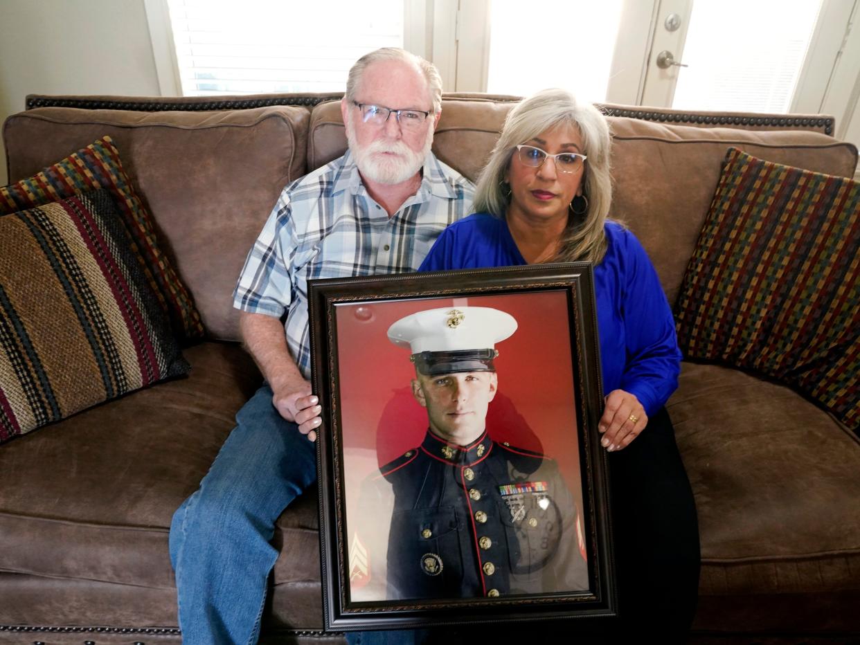 Joey and Paula Reed pose for a photo with a portrait of their son Marine veteran and Russian prisoner Trevor Reed at their home in Fort Worth, Texas, Feb. 15, 2022.