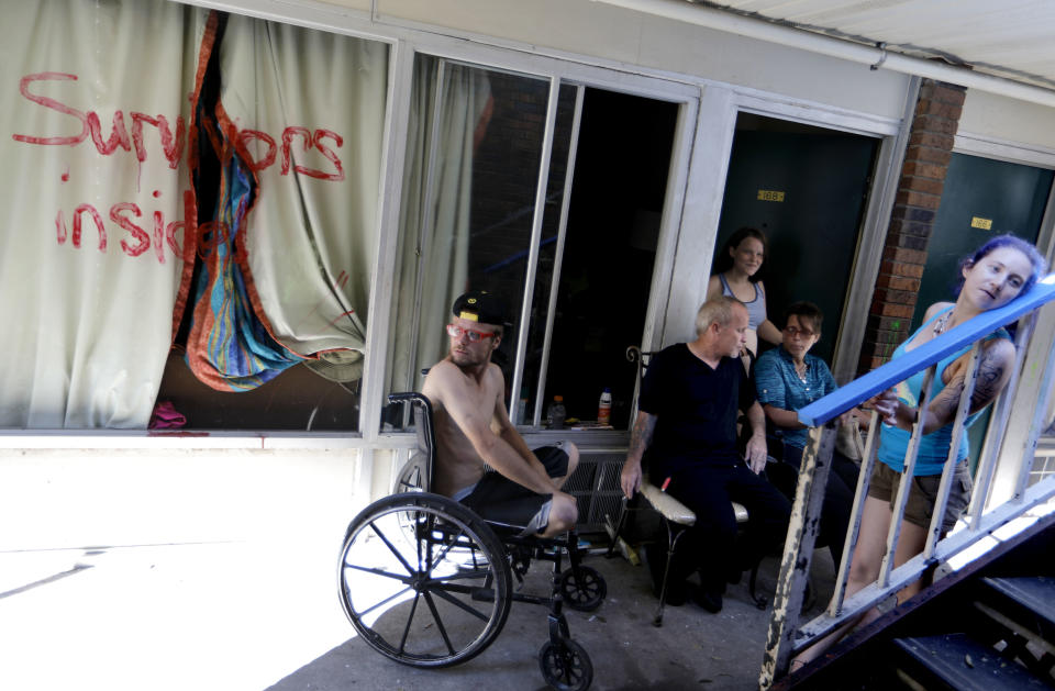 Wes Allen, Jr., from left, sits with his father Wes Allen, Sr., sister Alison, mother Vicki and fellow resident Crystal Williams outside their rooms at a damaged American Quality Lodge where they continue to live in the aftermath of Hurricane Michael in Panama City, Fla., Tuesday, Oct. 16, 2018. Families huddle under makeshift tents and in breezeways strewn with broken glass and roofing fragments, seeking escape from the midday sun as the temperature climbs to the mid-80s. (AP Photo/David Goldman)