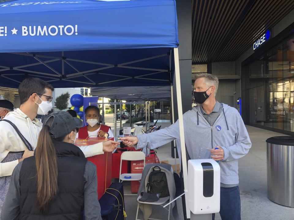 Golden State Warriors coach Steve Kerr hands out "I Voted" stickers at a ballot drop-off station at Chase Center in San Francisco on Saturday, Oct. 31, 2020. (AP Photo/Janie McCauley)