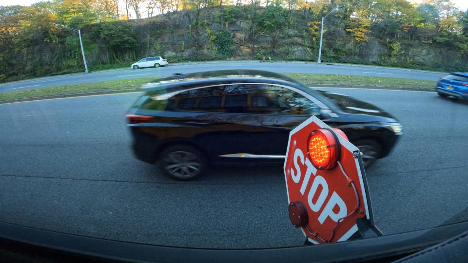 A cars drives past a school bus' flashing stop sign on Central Park Ave. in Yonkers. The First Student bus was taking students to the Casimir Pulaski School Weds. morning Nov. 8, 2023.