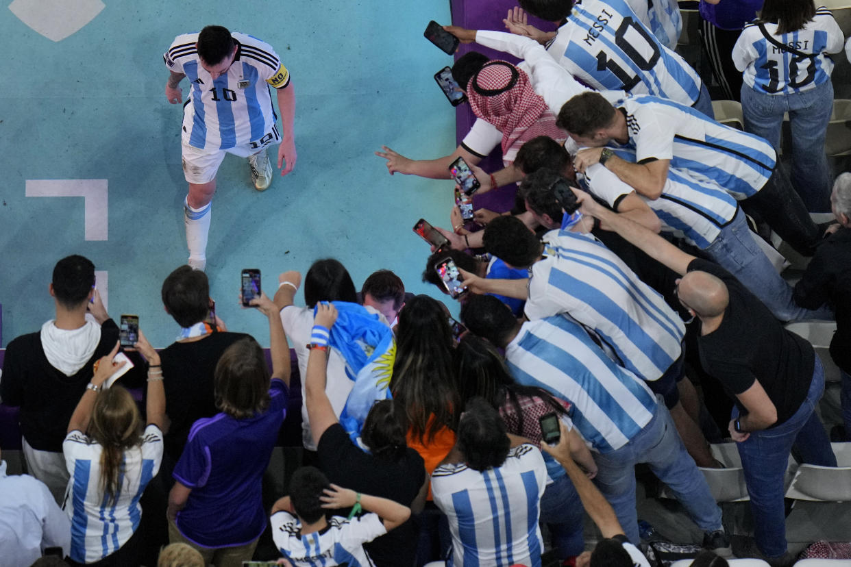 Fans take pictures of Argentina's Lionel Messi during the World Cup quarterfinal soccer match between the Netherlands and Argentina, at the Lusail Stadium in Lusail, Qatar, Friday, Dec. 9, 2022. (AP Photo/Hassan Ammar)