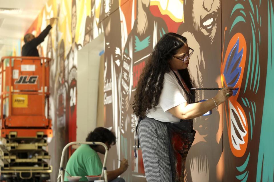 Three people work on a mural