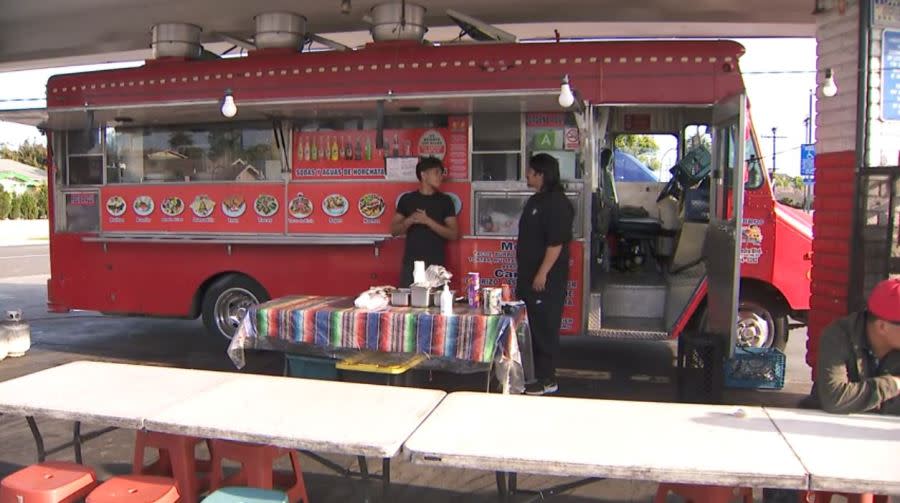 Erick Flores and a coworker outside of the Los Bros Tacos truck in Long Beach, California. (KTLA)