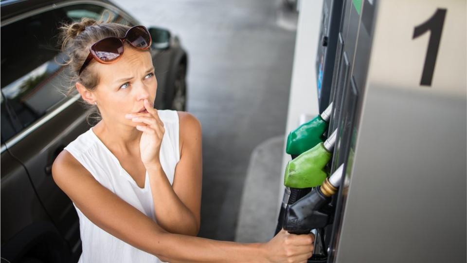 Mujer junto a un surtidor de gasolina