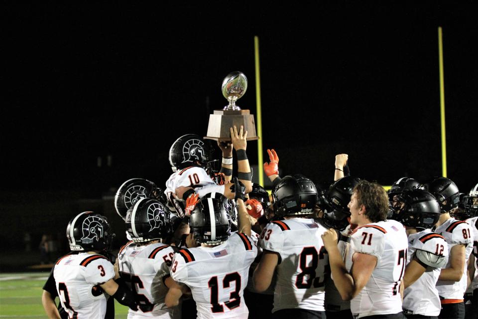 Sturgis senior quarterback Taner Patrick is hoisted up by his teammates following the Trojan win over Coldwater on Friday night.