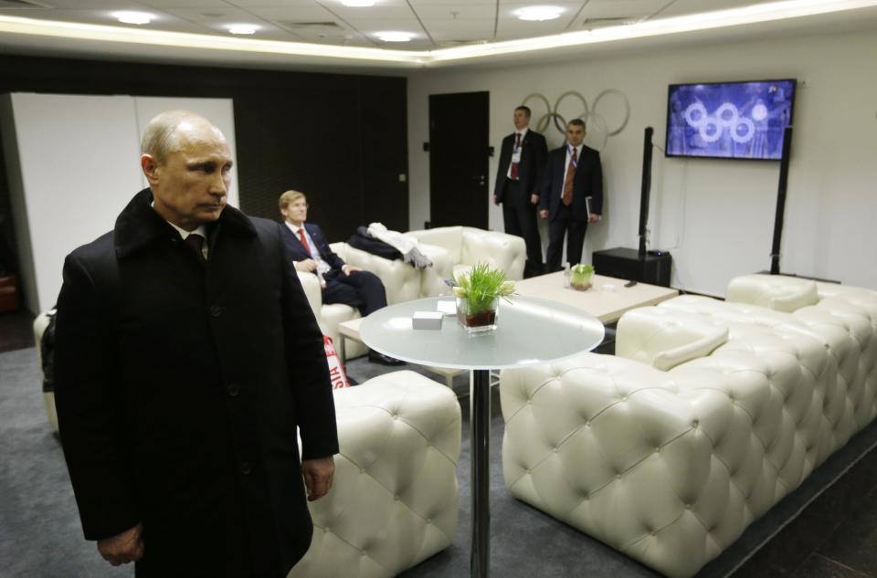 In this second in a sequence of four images, one second after the previous one, Russian President Vladimir Putin waits in the presidential lounge to be introduced at the opening ceremony of the 2014 Winter Olympics on Friday, Feb. 7, 2014, in Sochi, Russia. Behind him, a TV screen shows four of the Olympic rings almost fully open at the start of the ceremony, while the fifth ring remains closed. (AP Photo/David Goldman, Pool)