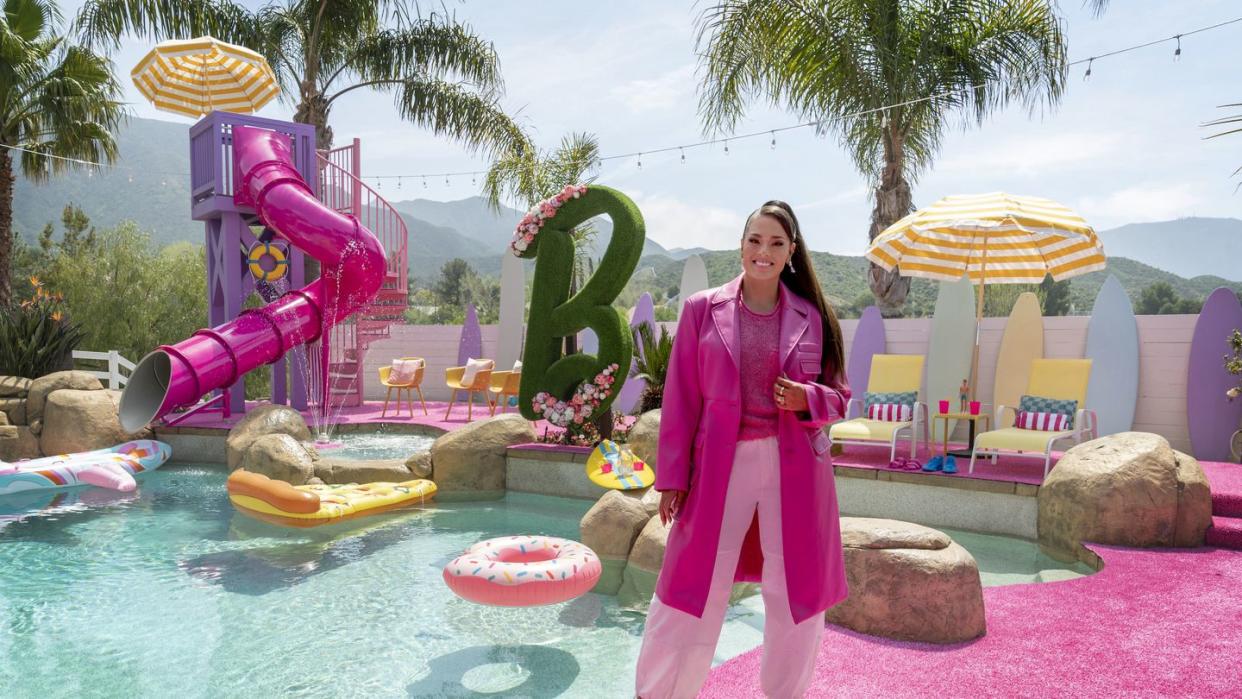 host ashley graham poses in the finished backyard, as seen on barbie dream house challenge, season 1