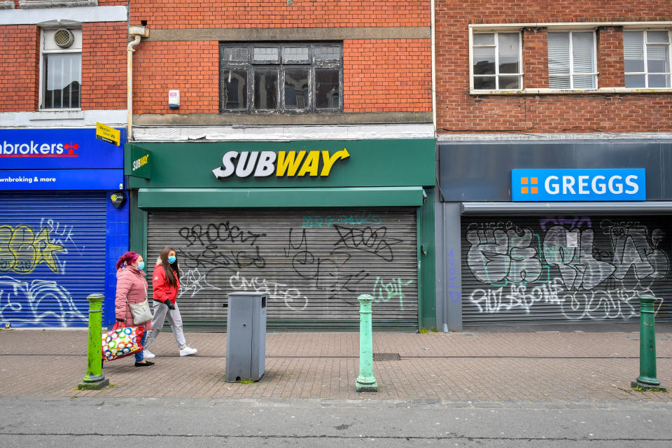 Two woman wearing face masks pass closed shops in Bedminster, Bristol as the UK continues in lockdown to help curb the spread of the coronavirus.